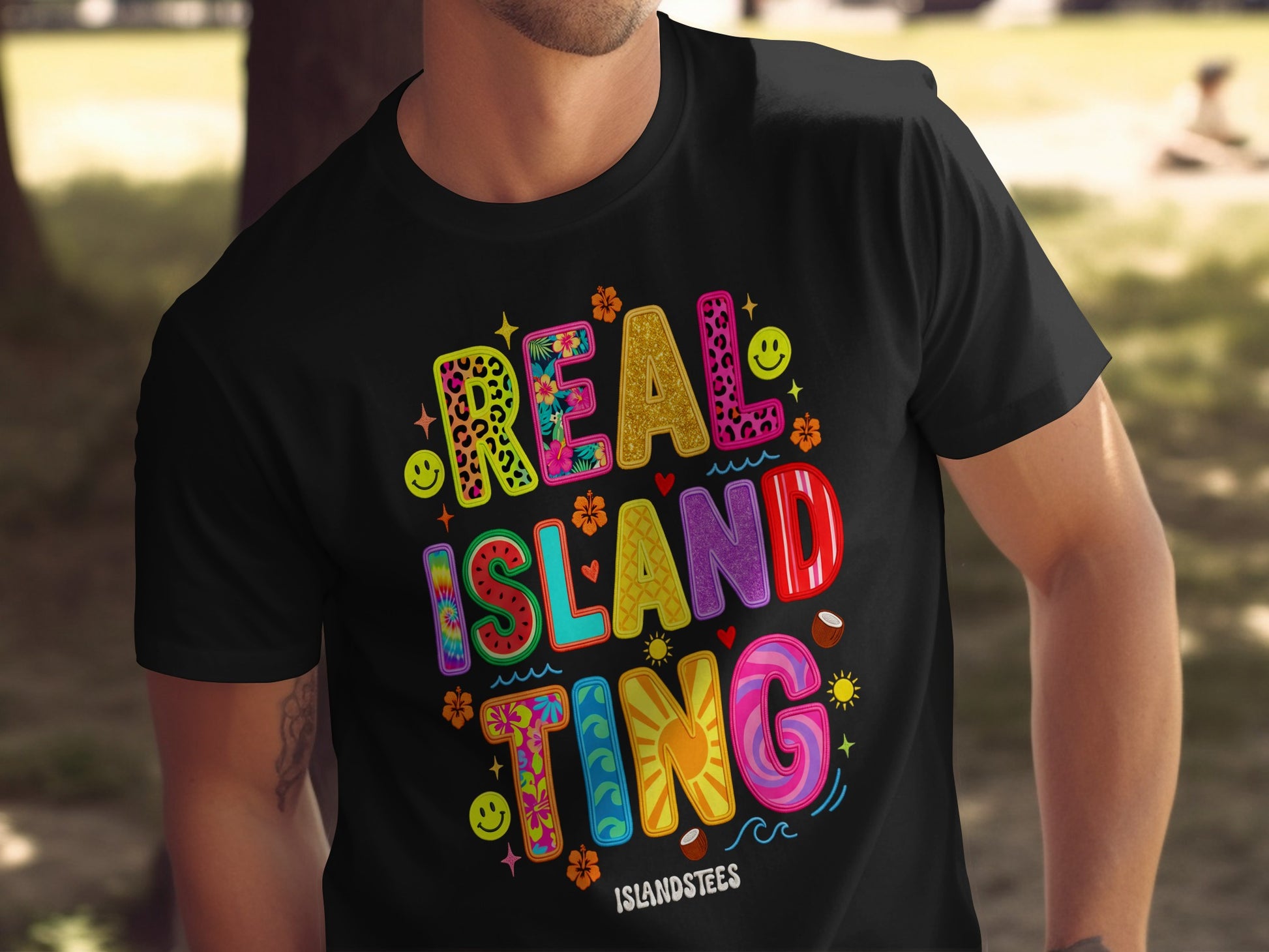 Black t-shirt with colorful "REAL ISLAND TING" text and tropical graphics.