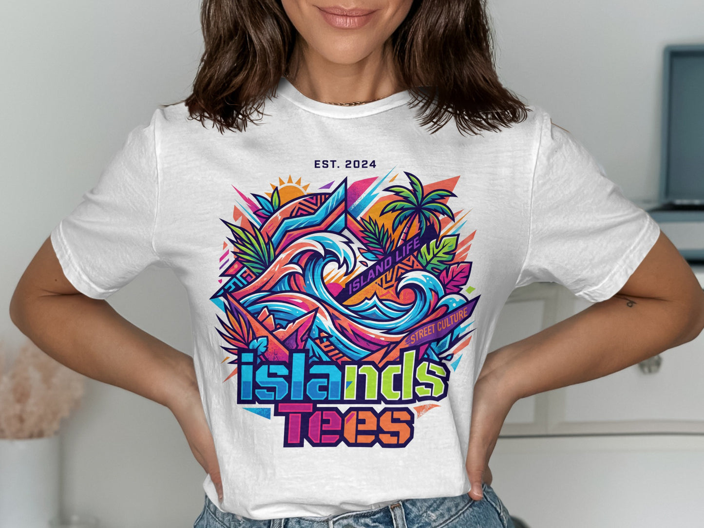 White t-shirt with vibrant "ISLANDS TEES" graphic, waves, palm trees, and "EST. 2024".