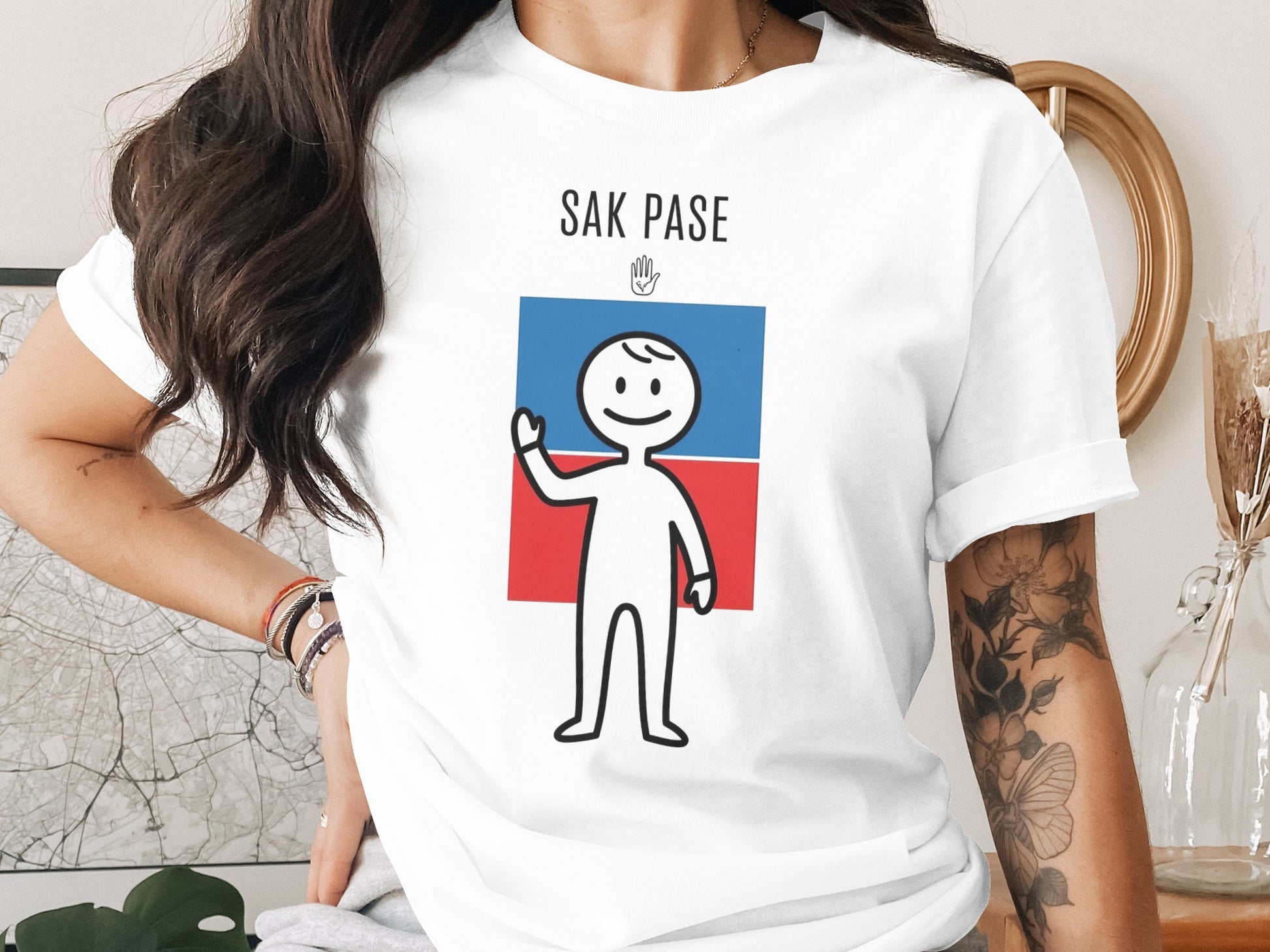 White t-shirt with "SAK PASE" text and a cartoon figure waving.