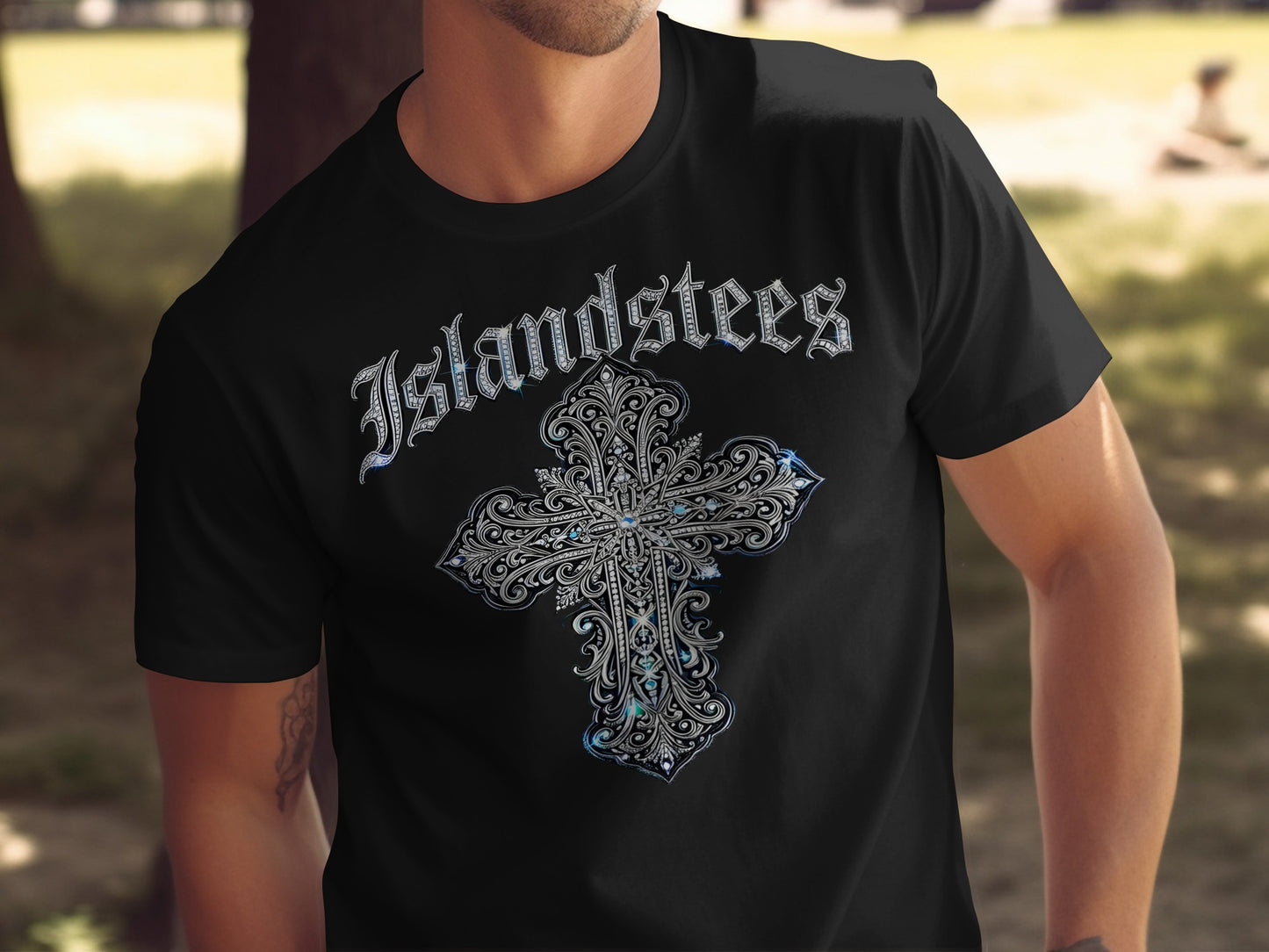 Black t-shirt with ornate silver cross design and "Islandstees" text.