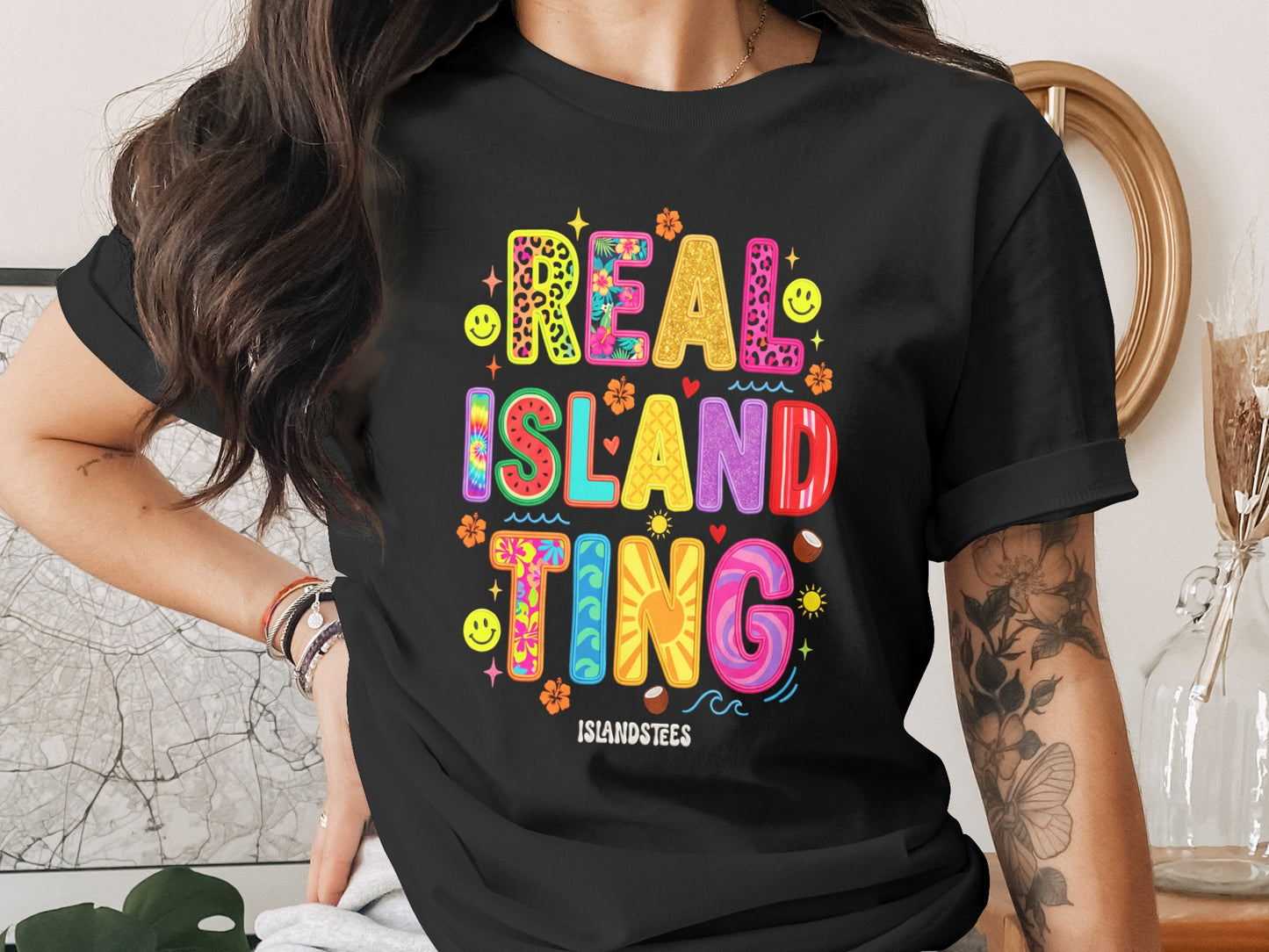 Black t-shirt with "REAL ISLAND TING" in colorful, patterned text.