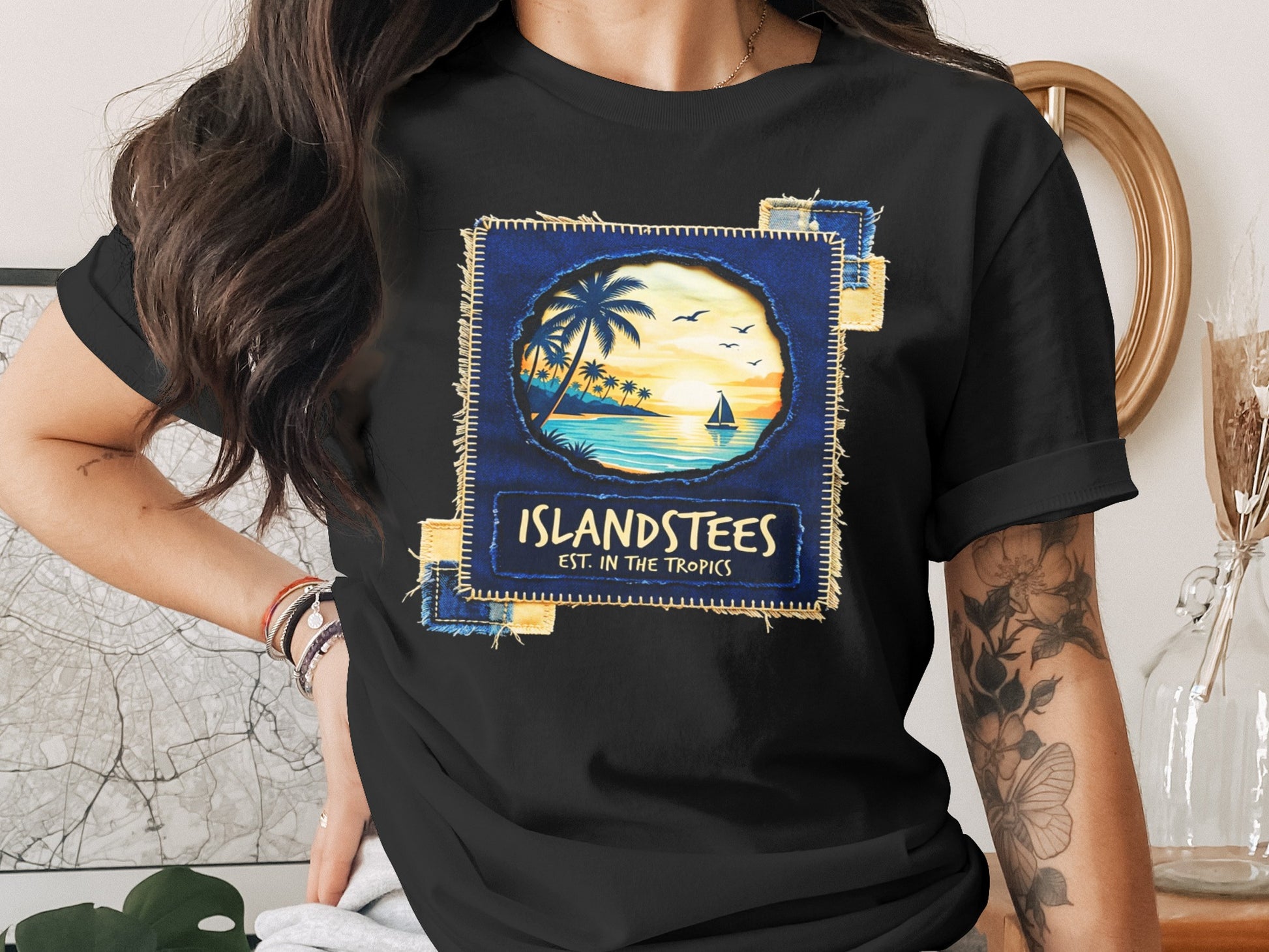 Black t-shirt featuring a tropical sunset scene with text "Islandstees est. in the tropics."